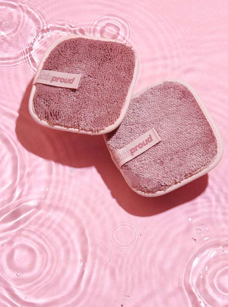 Two pink makeup remover pads splashing in water