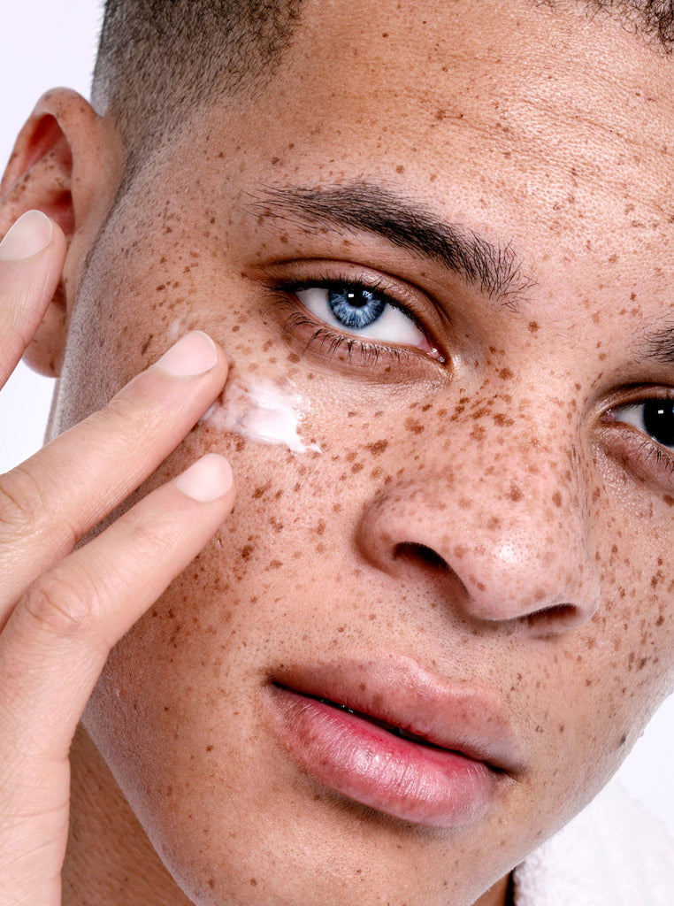 Male model with freckles applying Skin Proud Bright Eye cream